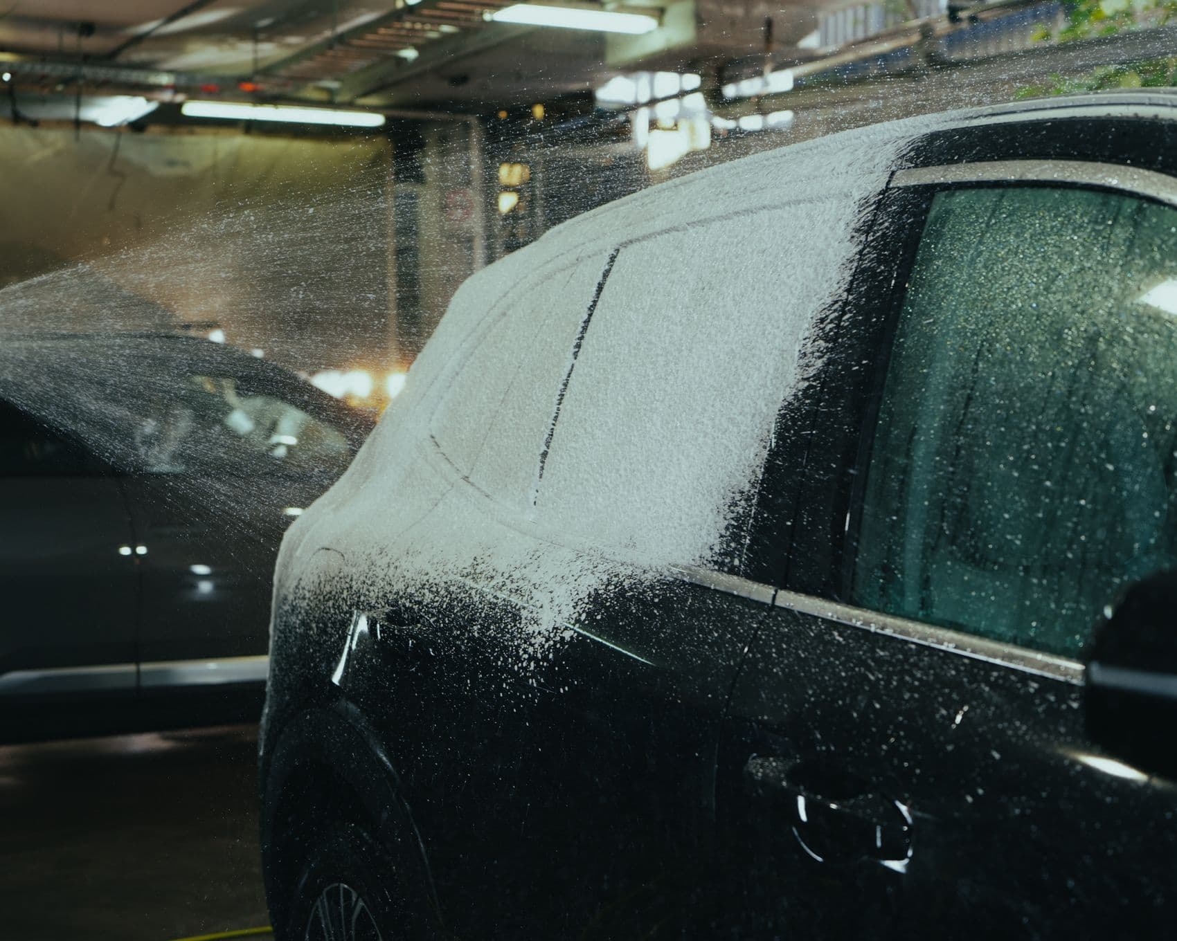 Snow foam clinging to the rear panels of an EV during a decontamination wash